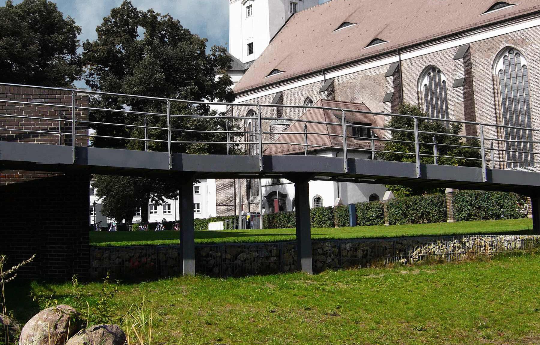 barrierefreie Erschließung über Metallsteg auf Wiese vor Denkmalgeschützter Kirche in Fürstenwalde